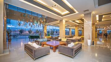 Un vestíbulo amplio con muebles modernos, ventanas grandes y lámparas colgantes.