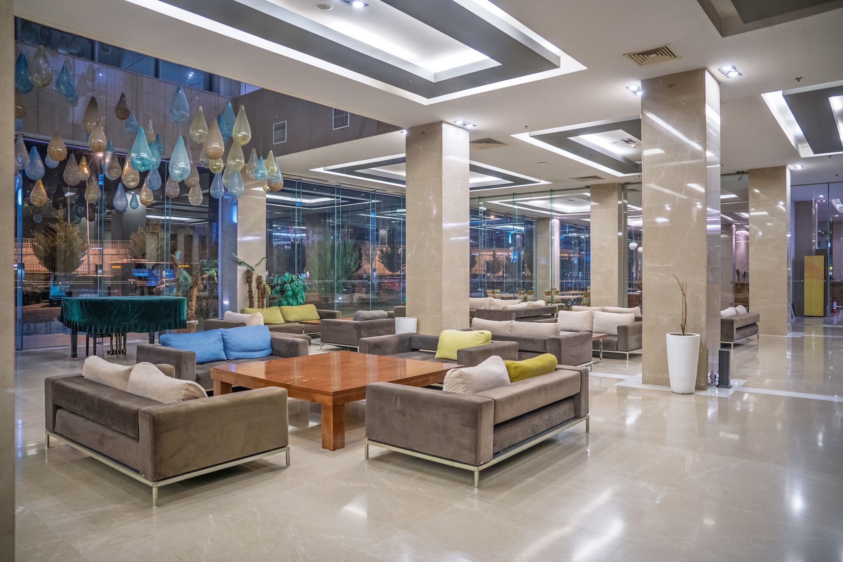 A spacious lobby with modern furniture, a large wooden coffee table, and hanging glass lamps.