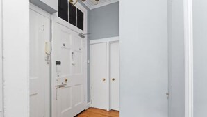 A hallway with white doors, wooden flooring, and a light blue wall. - First Floor-2 Bedroom Apartment (Edinburgh)