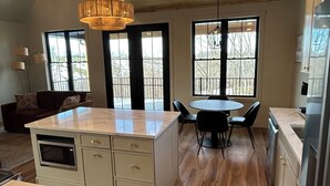 Een moderne keuken met een centraal eiland, houten vloeren en grote ramen.