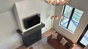 Een moderne woonkamer met een open haard, een bruine modulaire bank en een grote televisie.