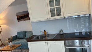 Cuina compacta amb armaris blancs, forn d'acer inoxidable i taulell de fusta.
