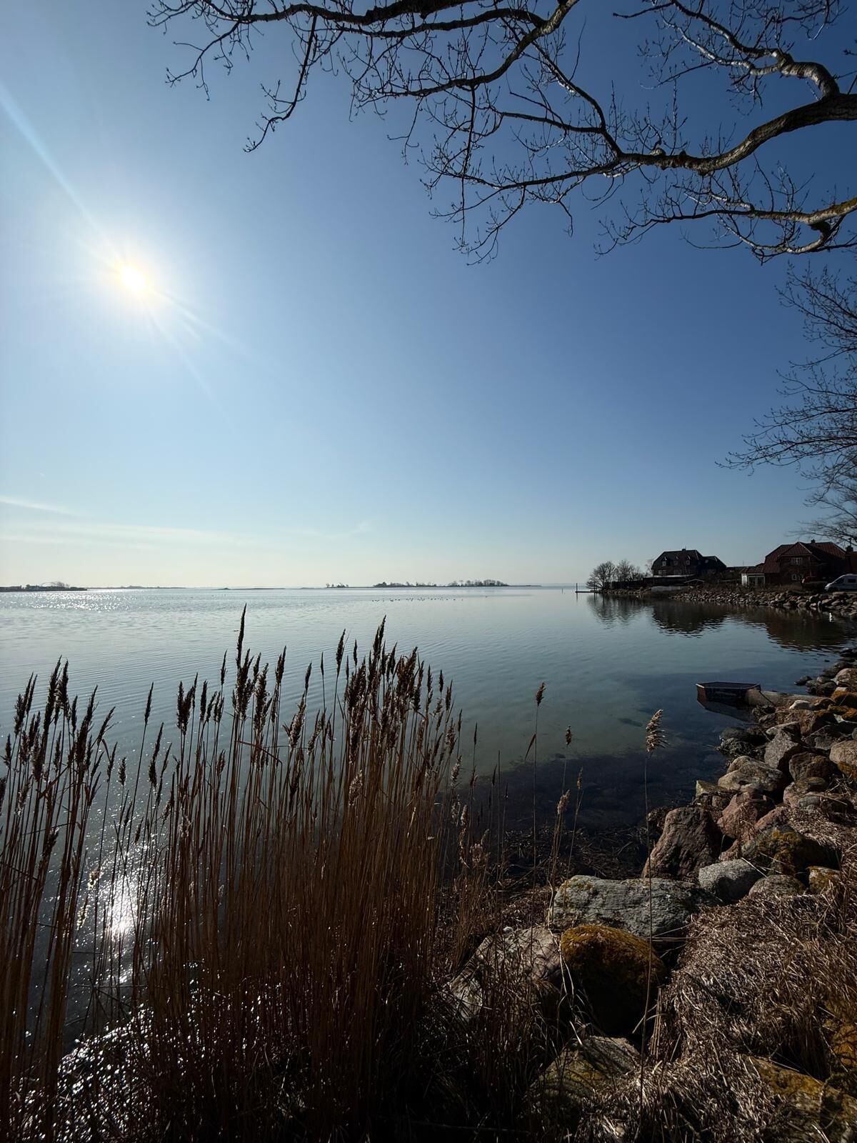 Een rustig meer met heldere lucht en een rotsachtige oever.