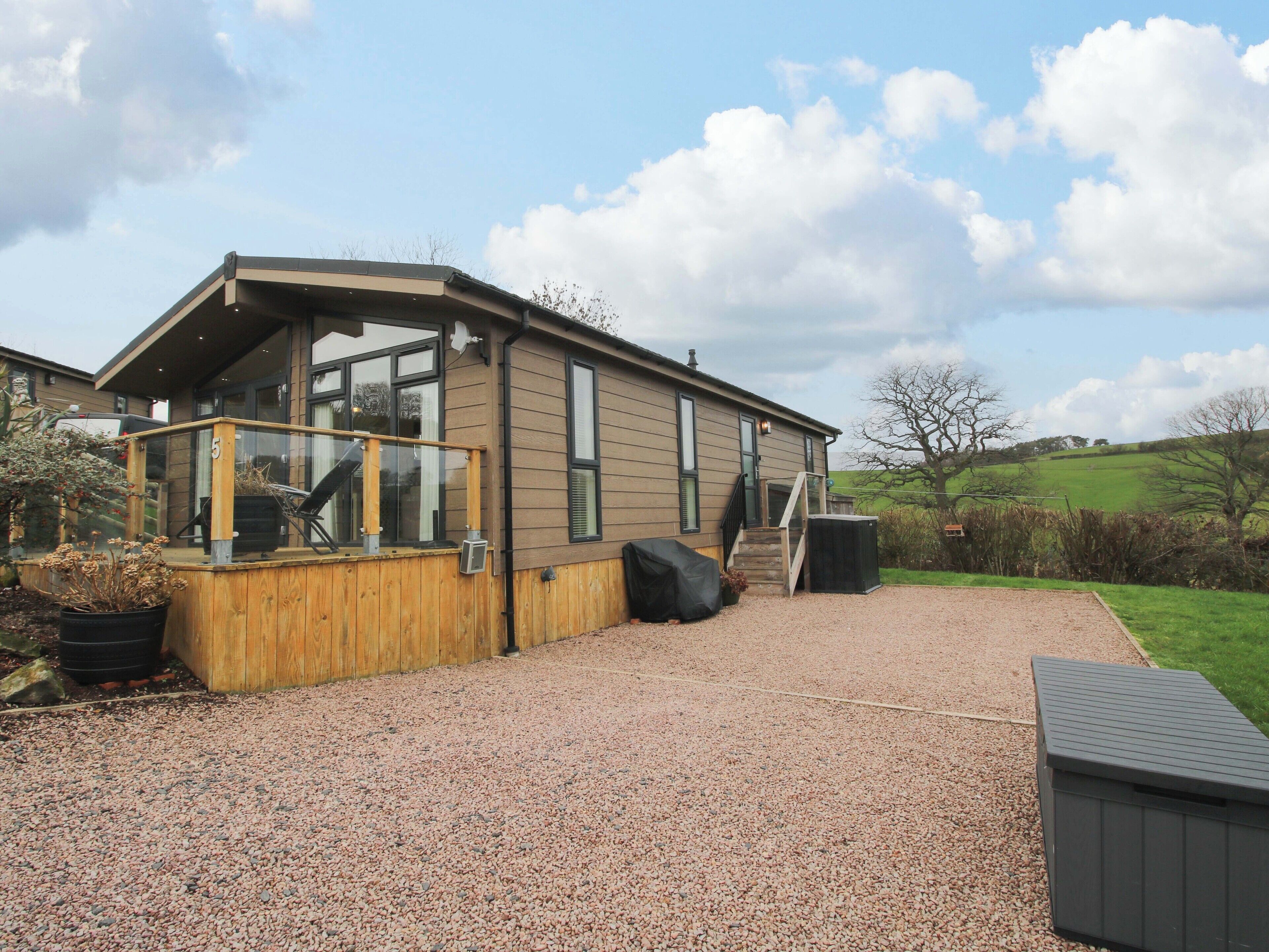 A modern house with a gravel driveway, wooden deck, and a covered outdoor area.