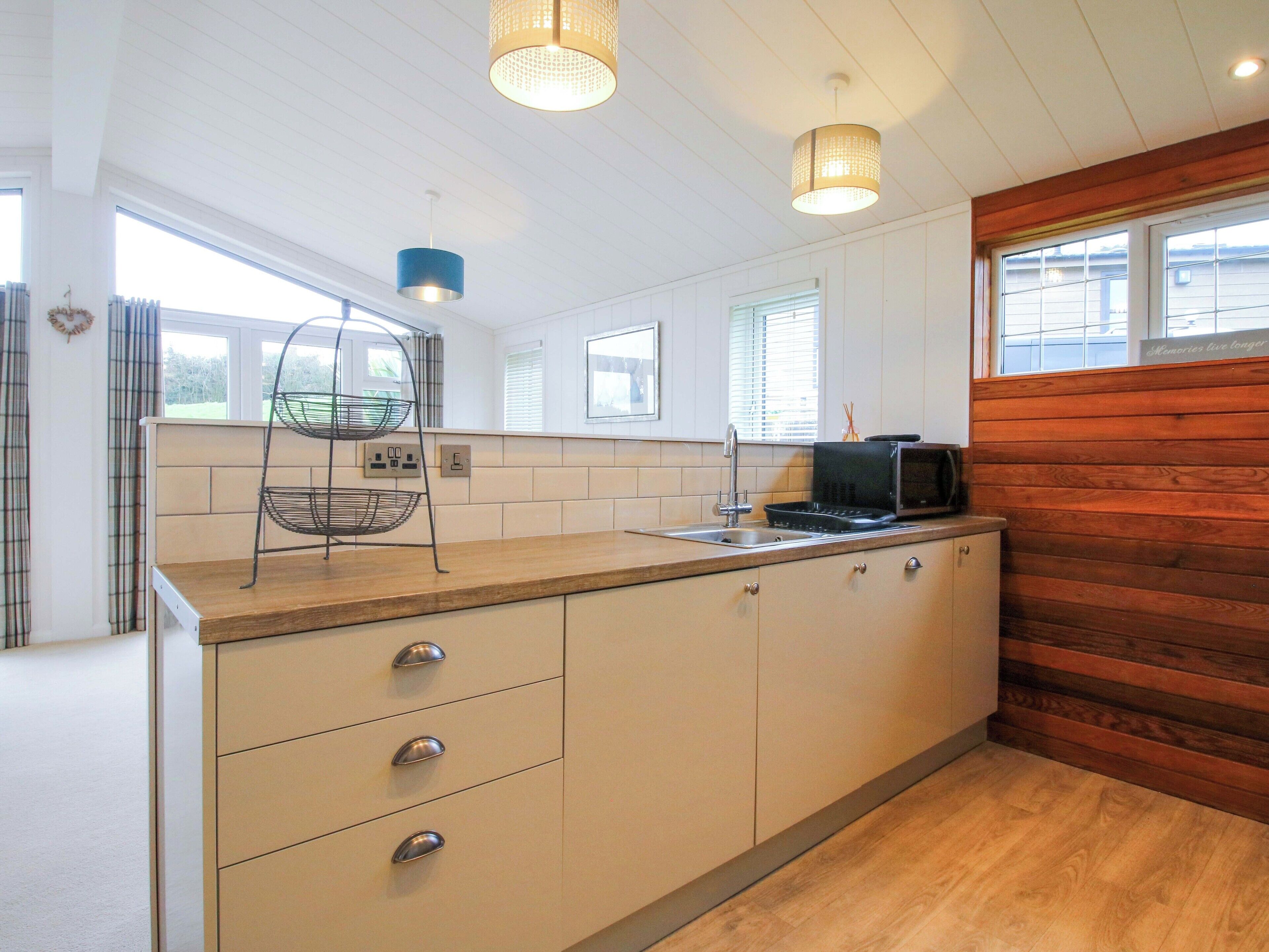 Una cocina con encimera de madera, microondas y una lámpara colgante.