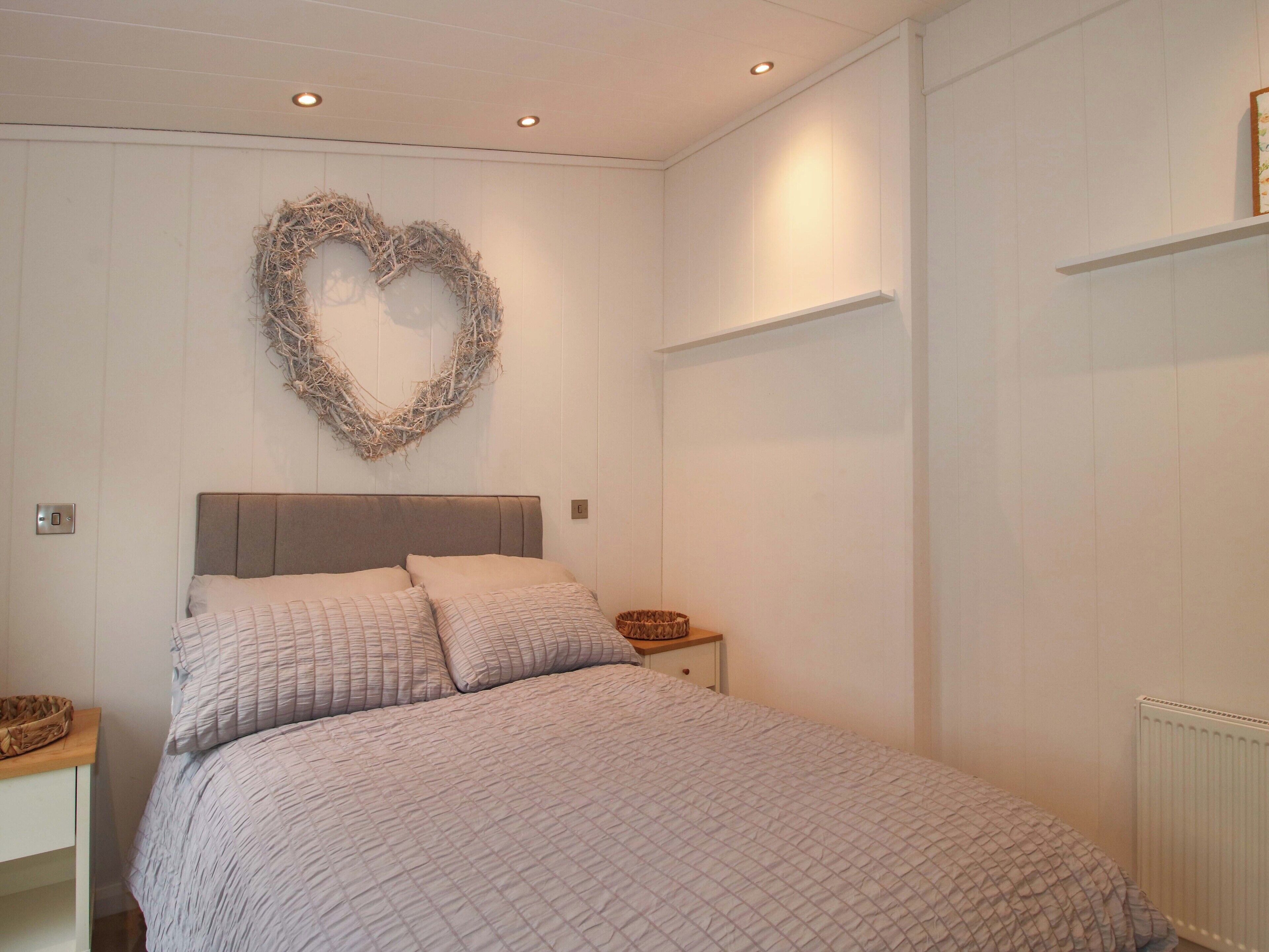 A bedroom with a bed, a heart-shaped wall decoration, and a white radiator.