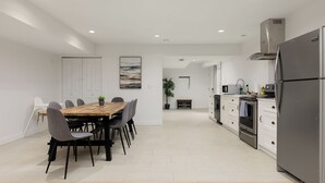 Cozinha moderna com ilha central, armários brancos e eletrodomésticos de aço inoxidável.