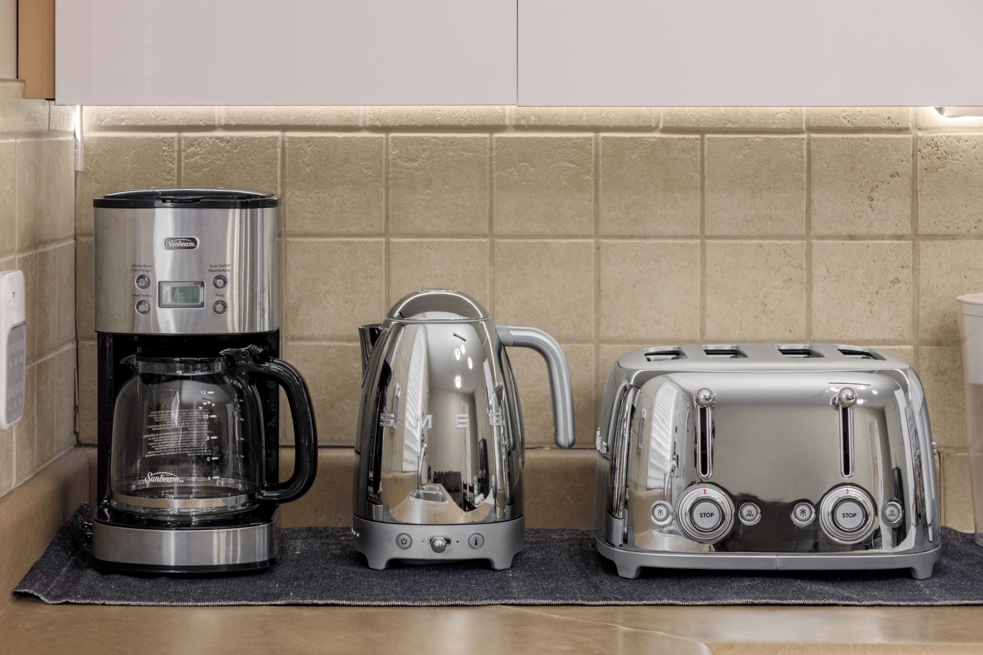 A kitchen with a coffee maker, a kettle, and a toaster on a countertop.