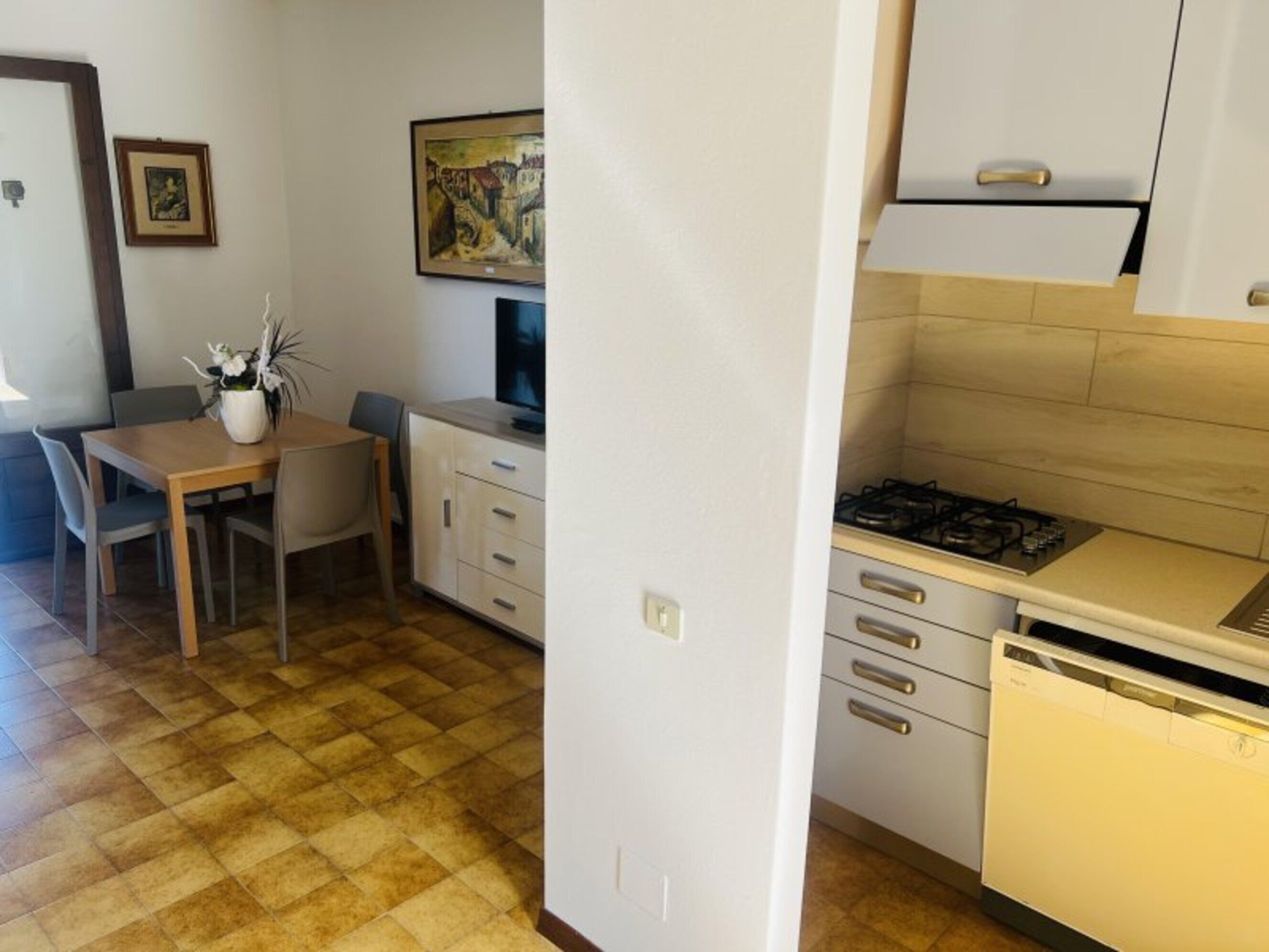 A compact kitchen with a gas stove, a dishwasher, and a dining area with a table and chairs.
