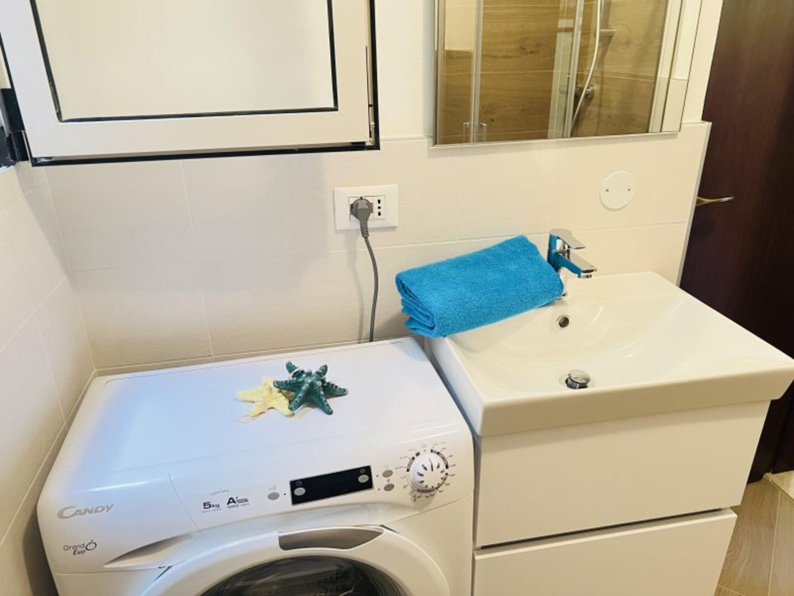Een kleine badkamer met een wasmachine, een wastafel en een spiegel.