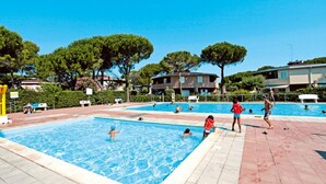 Zona de piscina con varias piscinas, rodeada de árboles y edificios.