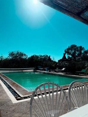 Una piscina al aire libre, sombrillas, sillones reclinables de piscina