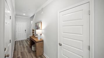 A hallway with a wooden floor, white walls, and a door on the right.