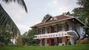 A two-story house with a balcony, surrounded by greenery.