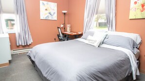 Un dormitorio con cama, escritorio, silla y ventana con cortinas.