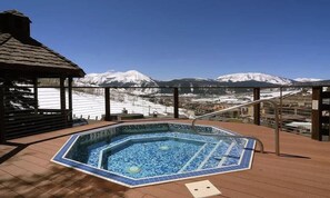 A hot tub with a view of snow-capped mountains, a wooden deck, and a gazebo. - Columbine 2104 (Crested Butte)