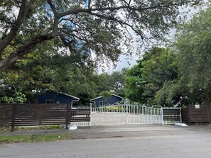 A gated area with a blue building, a wooden fence, and a metal gate. - FIFA ready Awesome 2-bedroom corporate apartment with AC in Hollywood Gated WiFi (Hollywood)