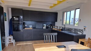 Una cucina moderna con mobili scuri, un tavolo da pranzo in legno e una finestra che lascia entrare luce naturale.