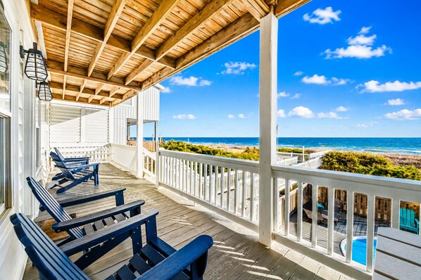 A wooden deck with benches overlooking a beach and ocean.