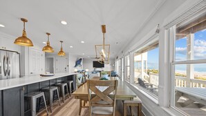 Une cuisine moderne dotée d’un îlot central, de tabourets de bar et de luminaires suspendus.
