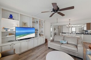 Ein Wohnzimmer mit Fernseher, Deckenventilator und einer Couch.