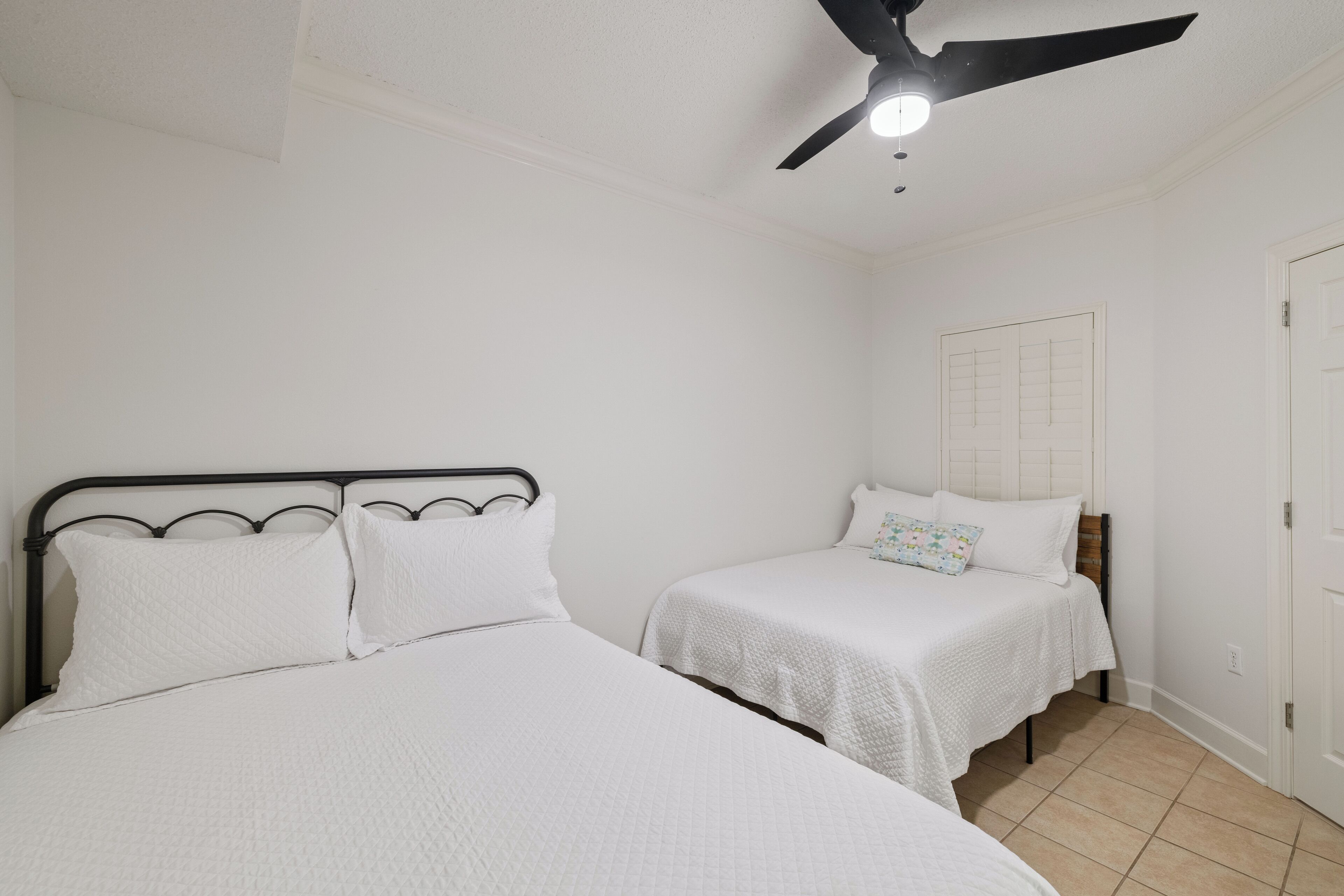 Ein Schlafzimmer mit zwei Betten, einem Deckenventilator und einer Tür.