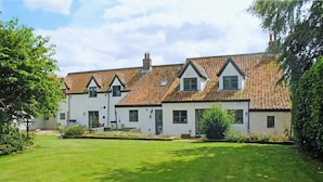 A row of white houses with red-tiled roofs and a well-maintained lawn.