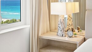 A hotel room with a large window, a bedside table with a lamp, a clock, and a small plant. - Oceanview Private Condo at 1 Hotel & Homes - 1207 (Miami Beach)