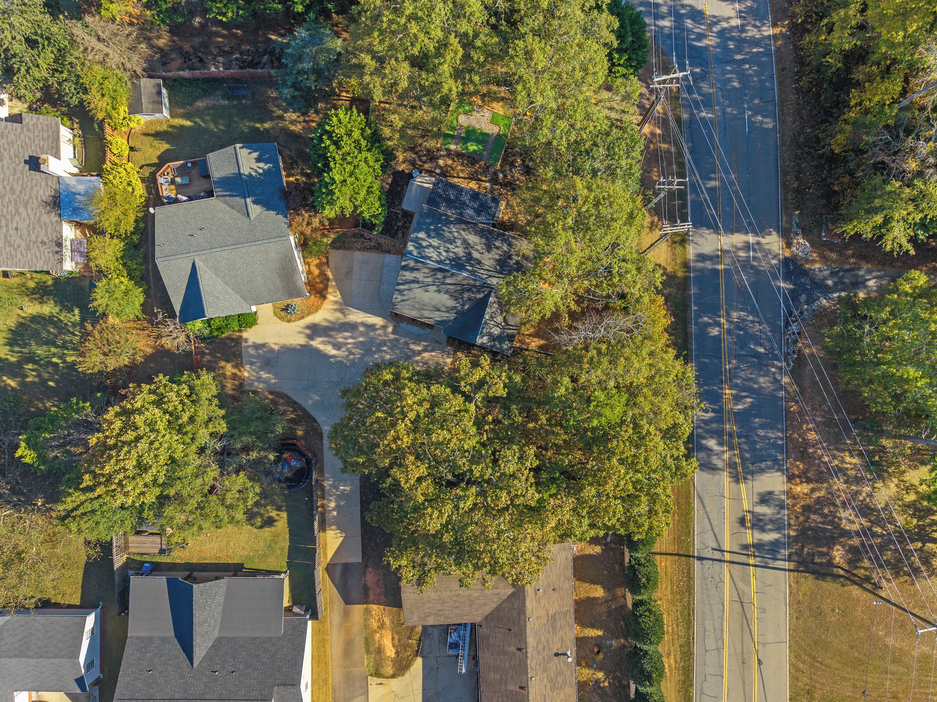 An aerial view of a residential area with houses, trees, and a road.
