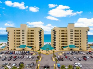 A hotel with a central courtyard, multiple parking lots, and a view of the ocean. - Gulf-front condo w/ beach access & pool (Panama City Beach)