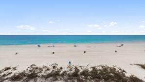 A beach with a clear sky, a sandy shore, and a few umbrellas. - Coastal 2BR - pool, beach access & daily tickets (Panama City Beach)