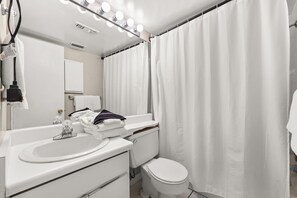 Une salle de bain avec un lavabo, un miroir et des toilettes.