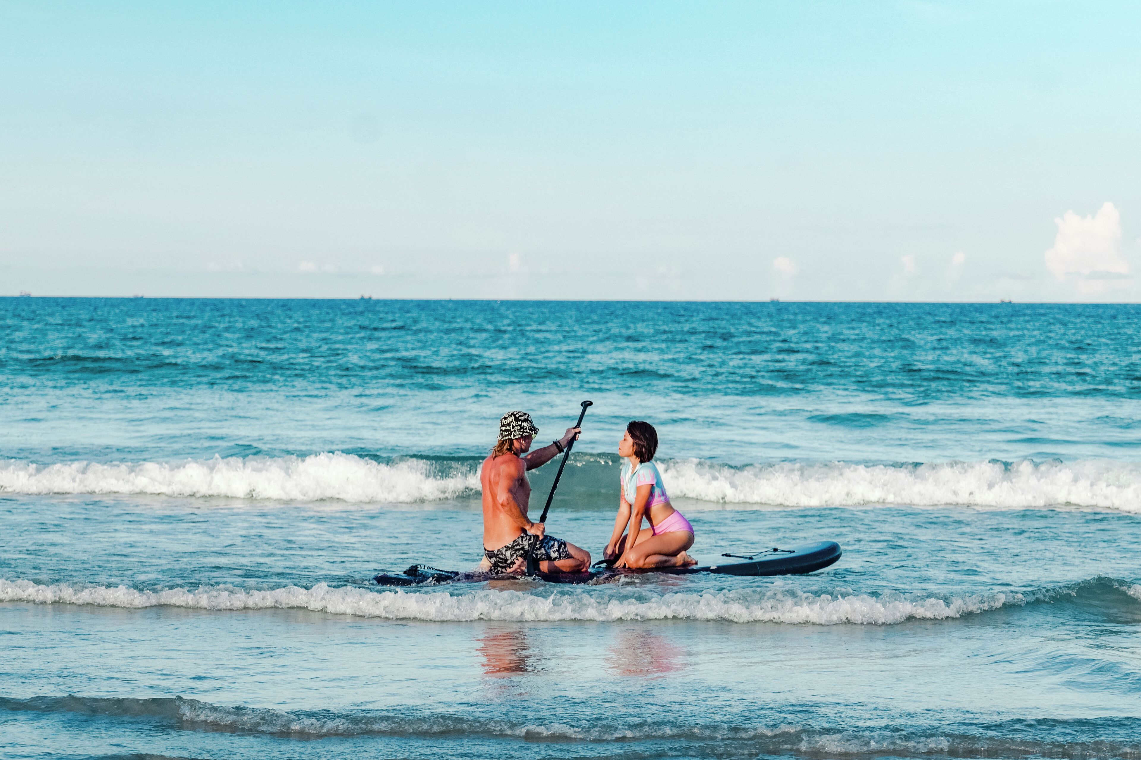 Two people on a paddleboard in the ocean.