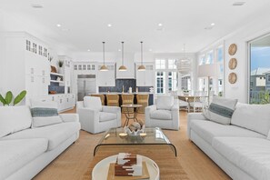 Ein modernes Wohnzimmer mit weißen Sofas, einem Glastisch und Pendelleuchten.