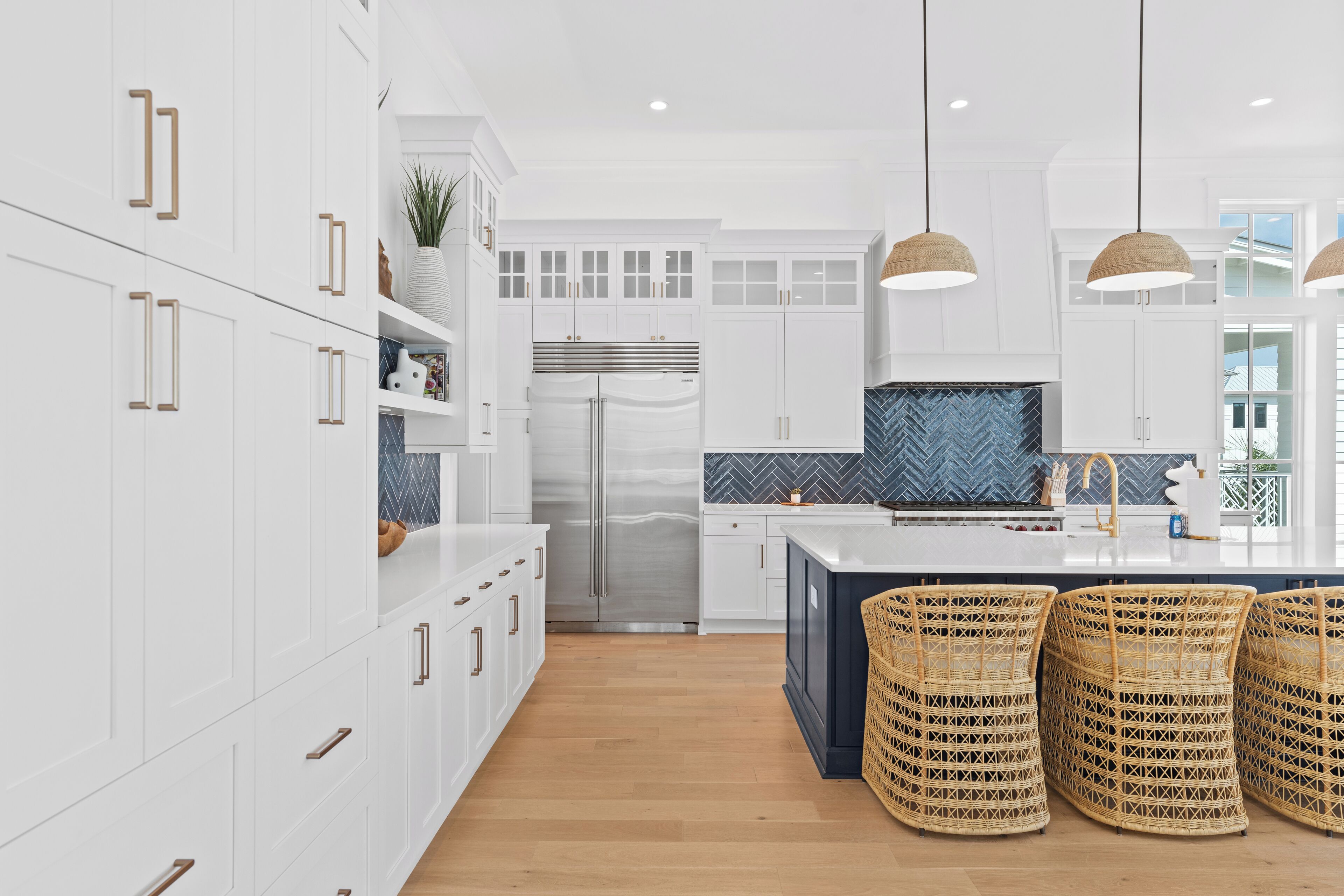 A modern kitchen with white cabinetry, a stainless steel refrigerator, and a herringbone tile backsplash.