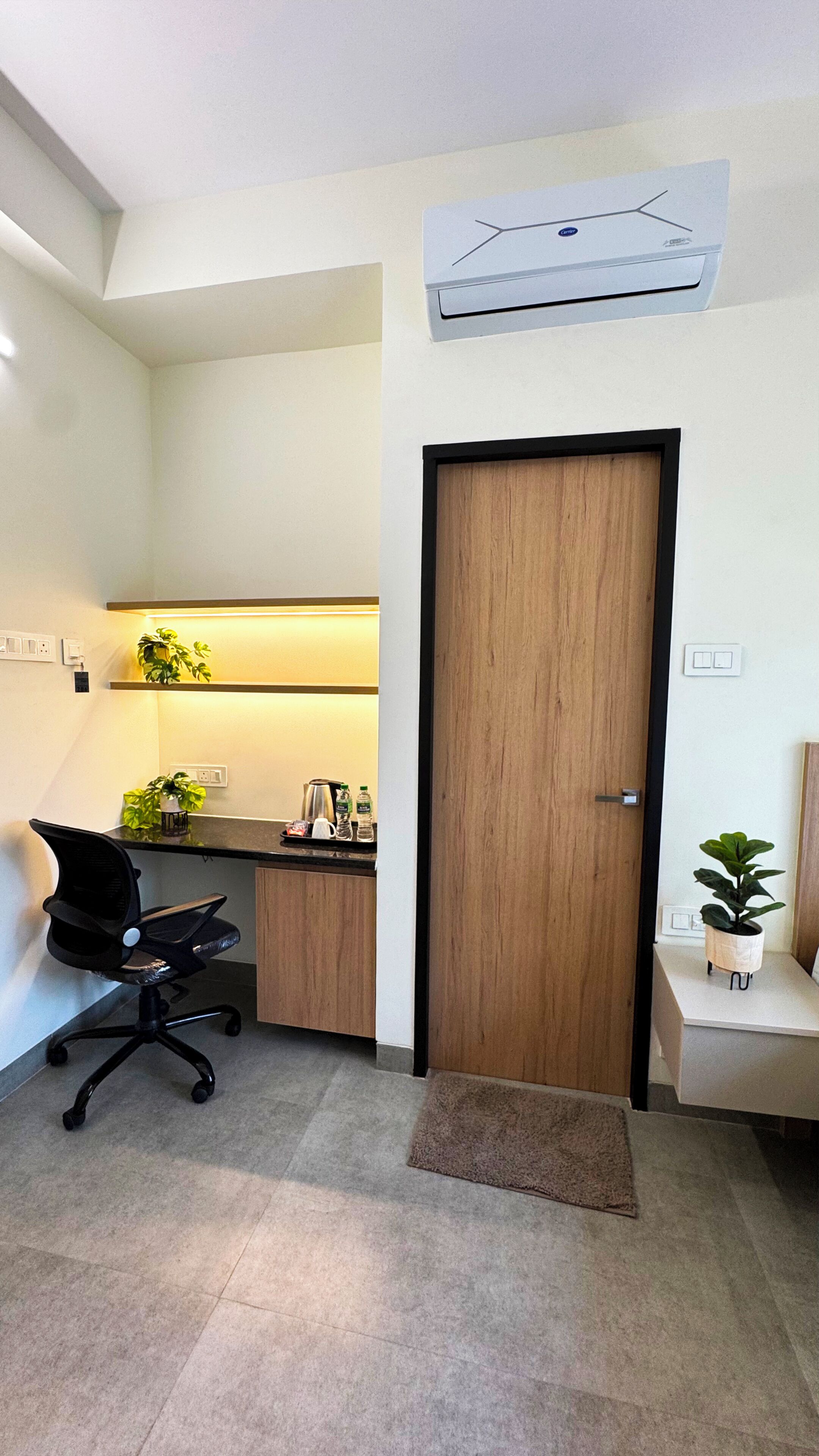 Un espacio de oficina moderno con un escritorio, una silla, plantas y un equipo de aire acondicionado.