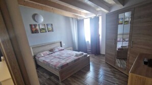 Une chambre avec un plancher en bois, un lit avec une tête de lit, une armoire et un miroir.