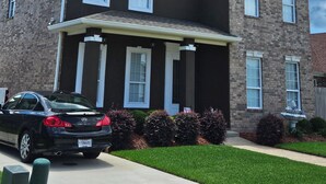 A two-story house with a dark brown exterior, white window frames, and a brick facade. - Charming 4-bedroom house with AC in lovely Meraux (Meraux)