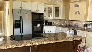 A kitchen with a central island, stainless steel appliances, and a hanging light fixture.