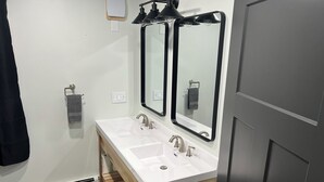 A bathroom with a white sink, two mirrors, and a towel rack. - Comfort and warmth, convenience to Campus at Pike Bay Apartment (Chassell)