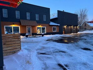 A modern building with large windows, a wooden fence, and a snow-covered ground.