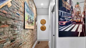 Un pasillo con pared de ladrillo, suelo de madera y dos adornos de madera en la pared.