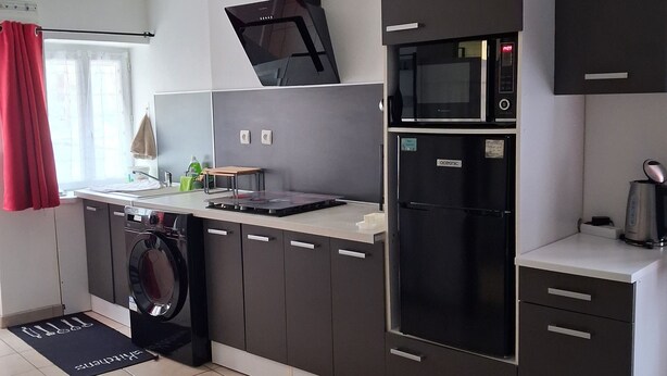 Une cuisine moderne équipée d’un lave-linge, d’un four à micro-ondes et d’un réfrigérateur.