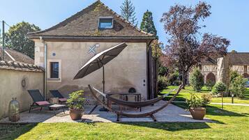 A house with a sloped roof, a hammock, lounge chairs, and potted plants.