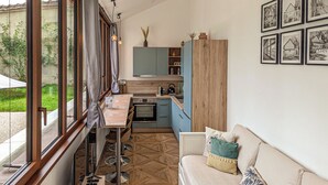 A compact kitchen with a dining area, a sofa, and a view of the outdoors. - La Maison T&M: Le Pigeonnier (Dosches)