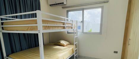 A bunk bed room with a window, air conditioning unit, and tiled floor.