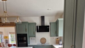 A modern kitchen with light green cabinets, a central island, and a built-in oven. - Luxurious 4-bedroom house perfect for relaxing stays in Cong (Cong)