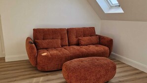 A modern living room with a brown sofa and ottoman, wooden flooring, and a skylight. - Luxurious 4-bedroom house perfect for relaxing stays in Cong (Cong)