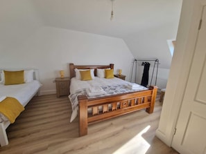 Une chambre à coucher avec un lit en bois, deux tables de chevet avec des lampes, un radiateur et une fenêtre.