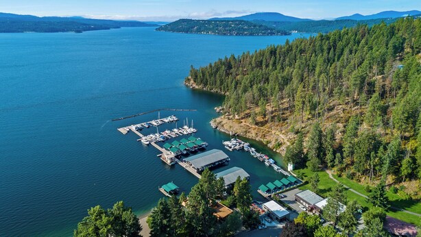 An aerial view of a marina with docks, boats, and buildings surrounded by dense forest and mountains. - New Listing! Walk to Downtown CDA | Pet-Friendly | Yard + Grill (Coeur D Alene)